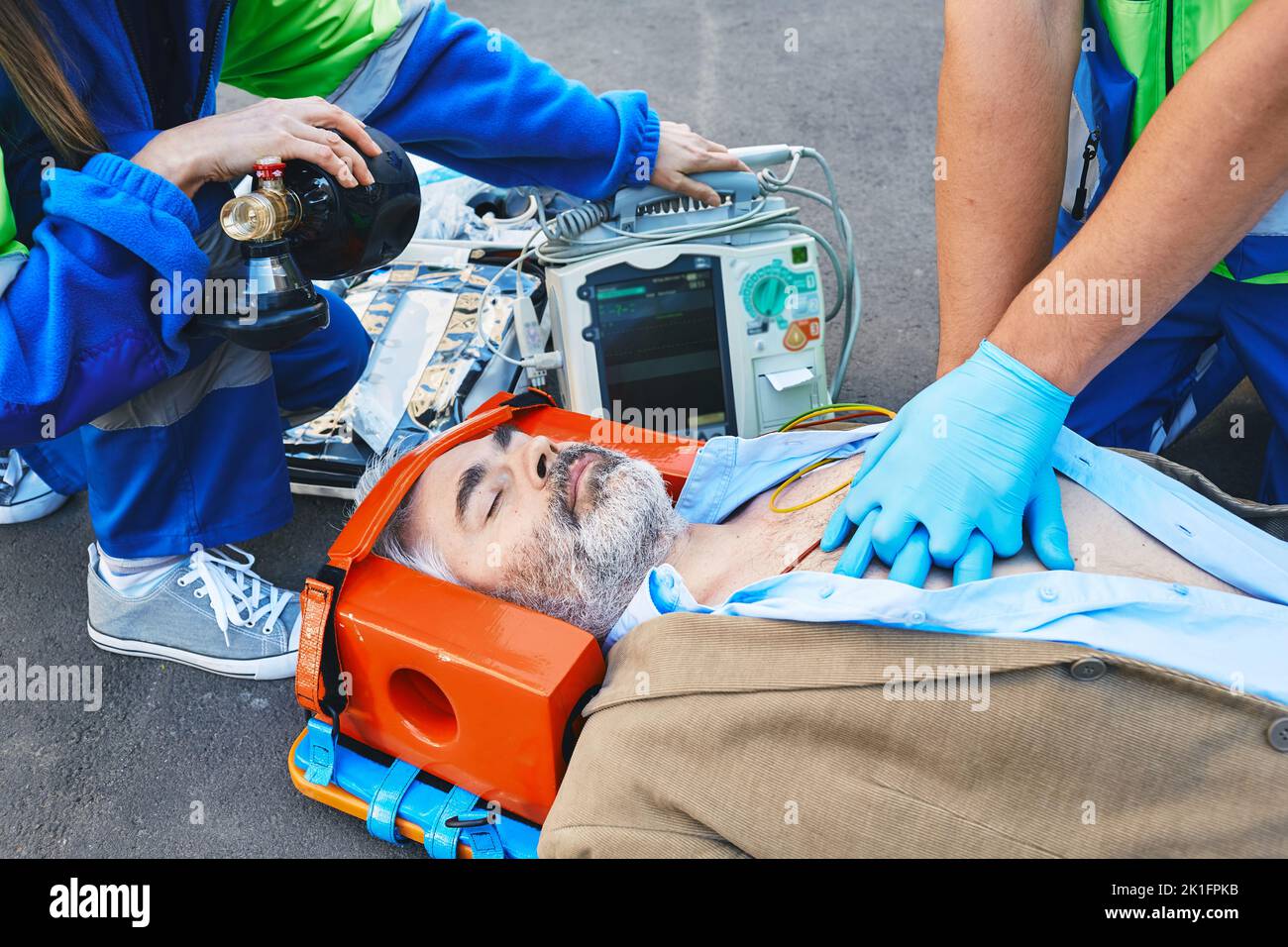 Paramedics provide first aid to victim man with medical equipment, give heart massage and CPR to patient to save his life Stock Photo