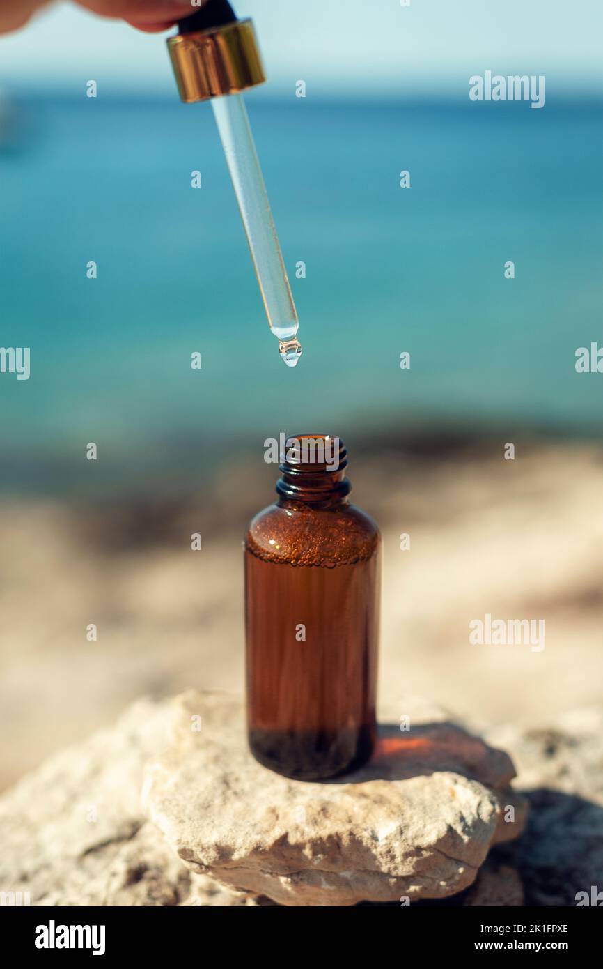 Cosmetic serum bottle and pipette on the background of the sea. Closeup