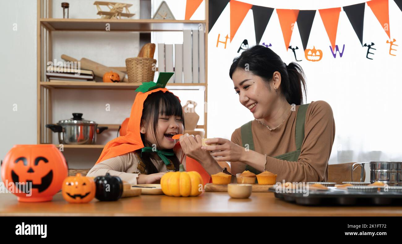 Mother and her daughter having fun at home. Happy Family preparing for Halloween. Mum and child cooking festive fare in the kitchen. Stock Photo