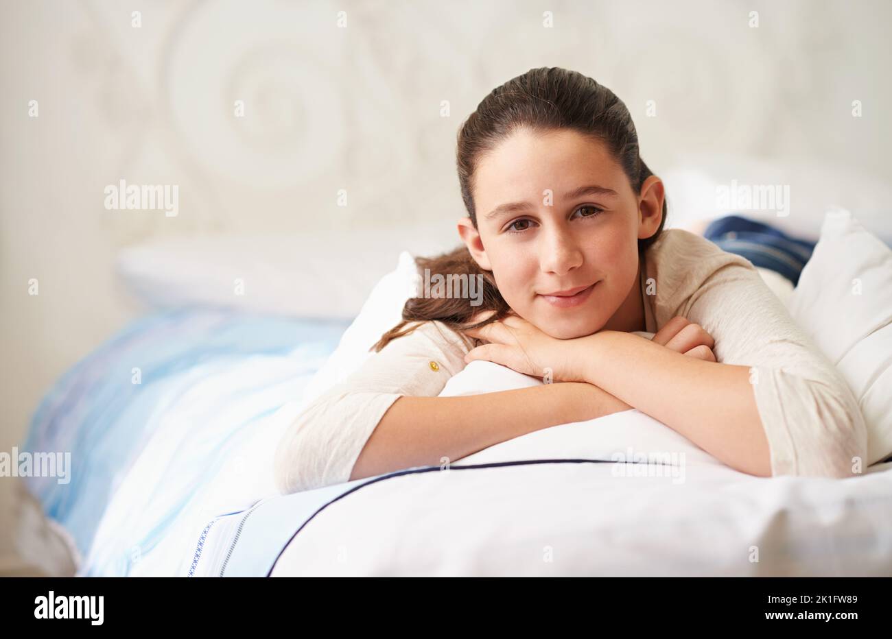 Relaxing in her room. a happy teenage girl lying on her bed. Stock Photo