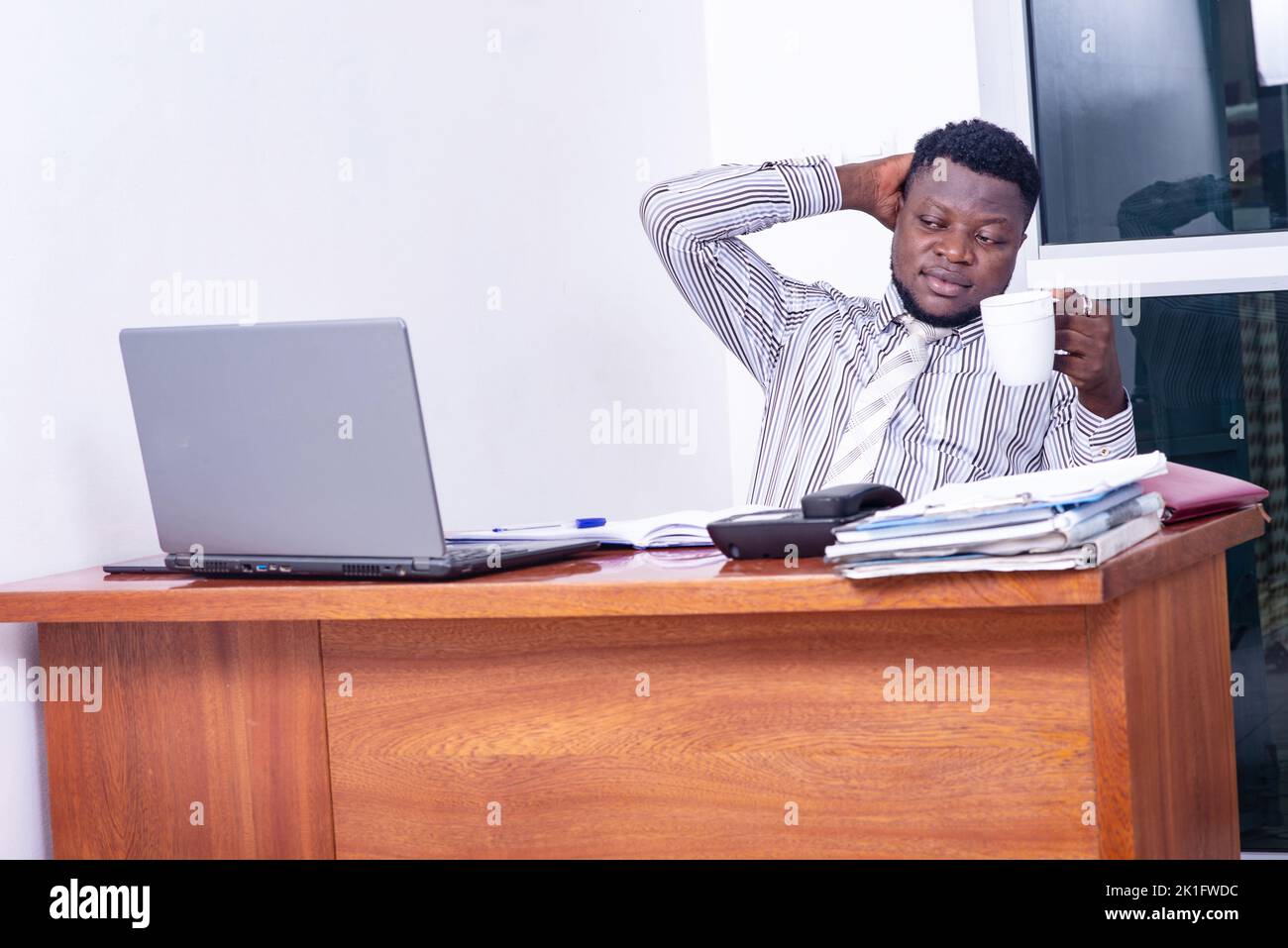 adult businessman sitting at the desk, facing the computer holding a ...