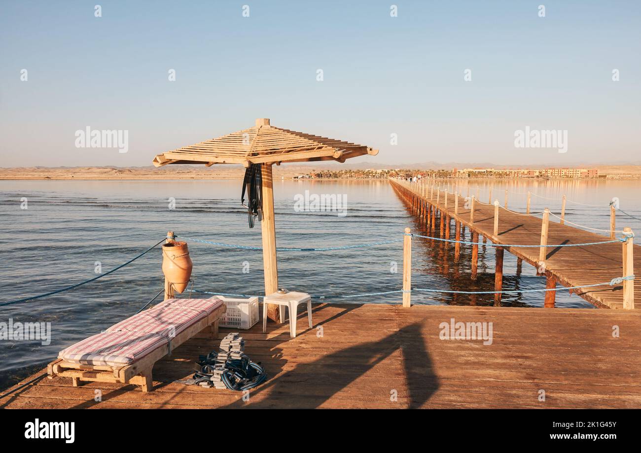Wooden sun umbrella, sunbed and diving weights on a pier platform, Marsa Alam, Egypt. Stock Photo