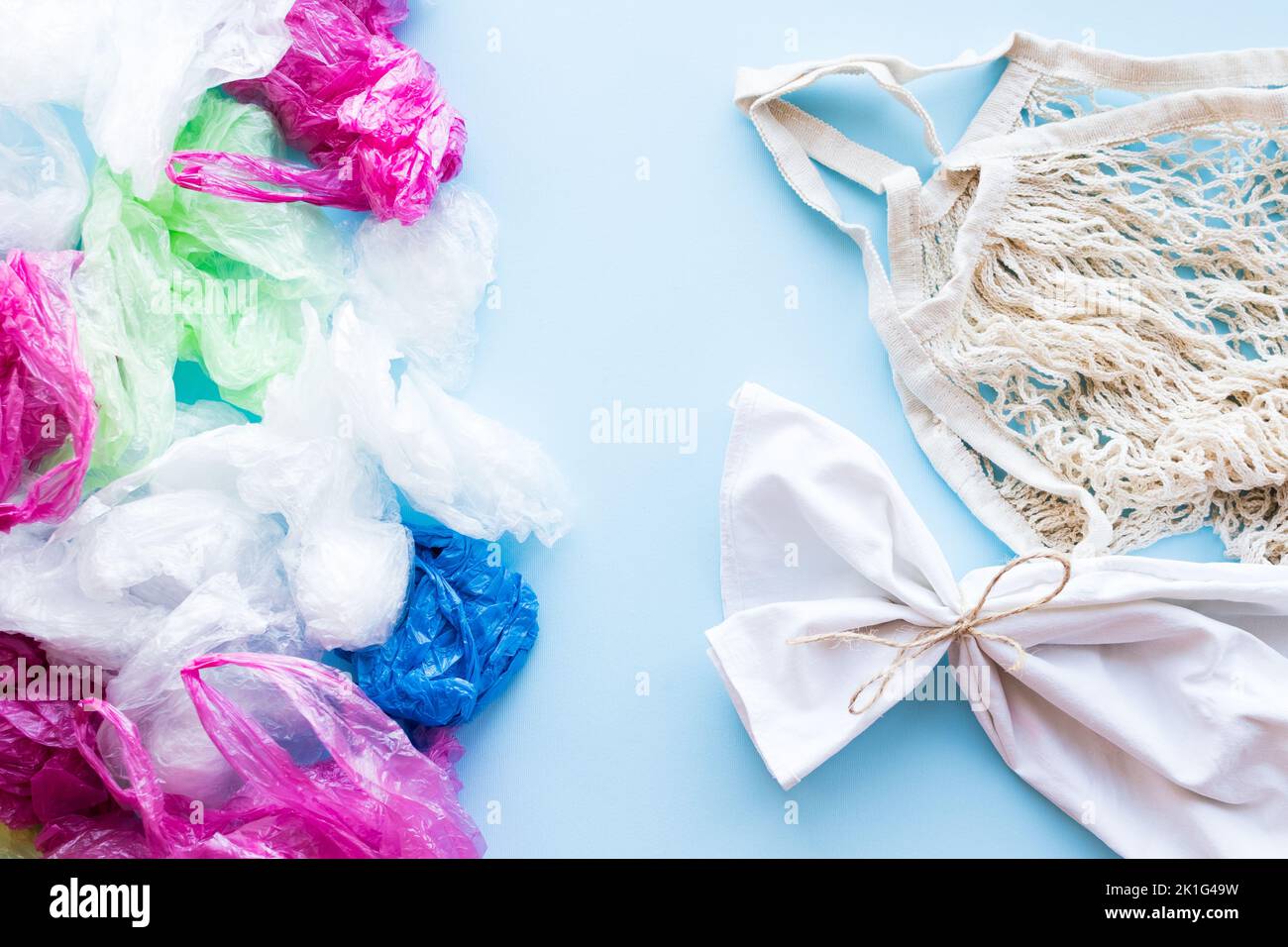 Many disposable plastic bags vs reusable cotton bags on a blue