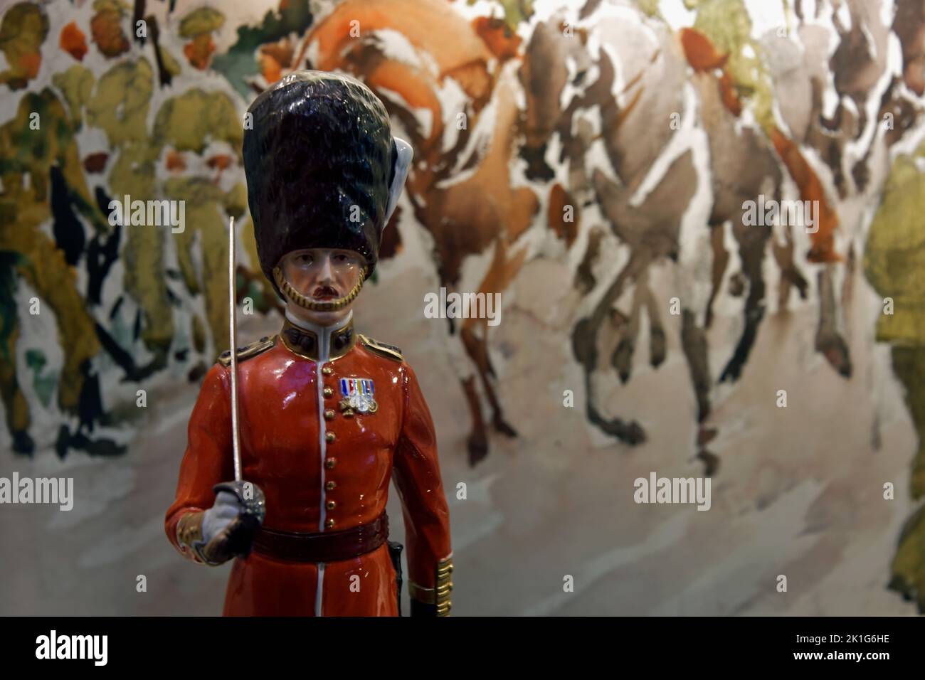 Small british figurine of al foot guards against a painting with horses Stock Photo