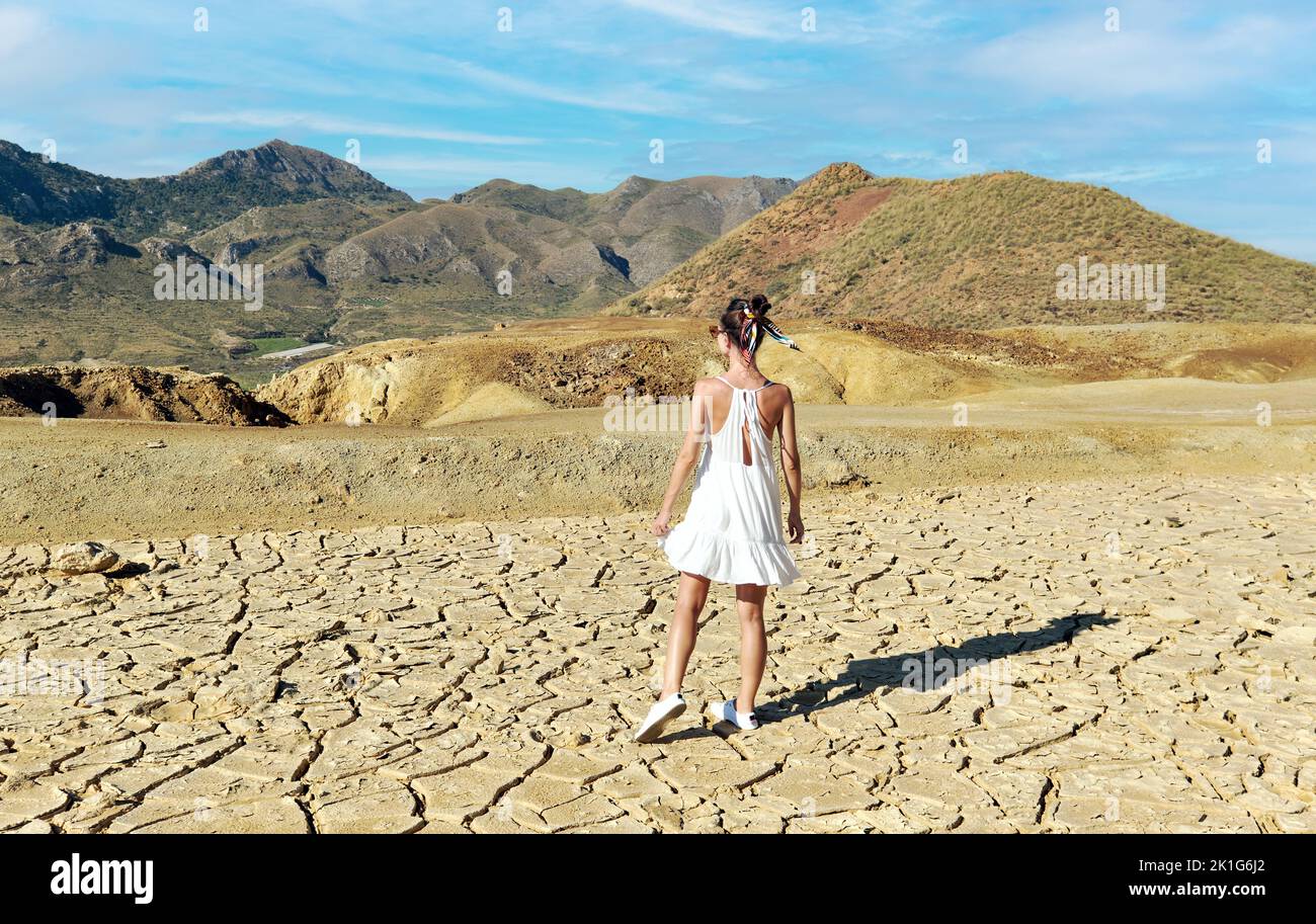 Rear view young female tourist in white dress visit old abandoned mines of Mazarron in Murcia on blue sky background during sunny summer day. Travel d Stock Photo