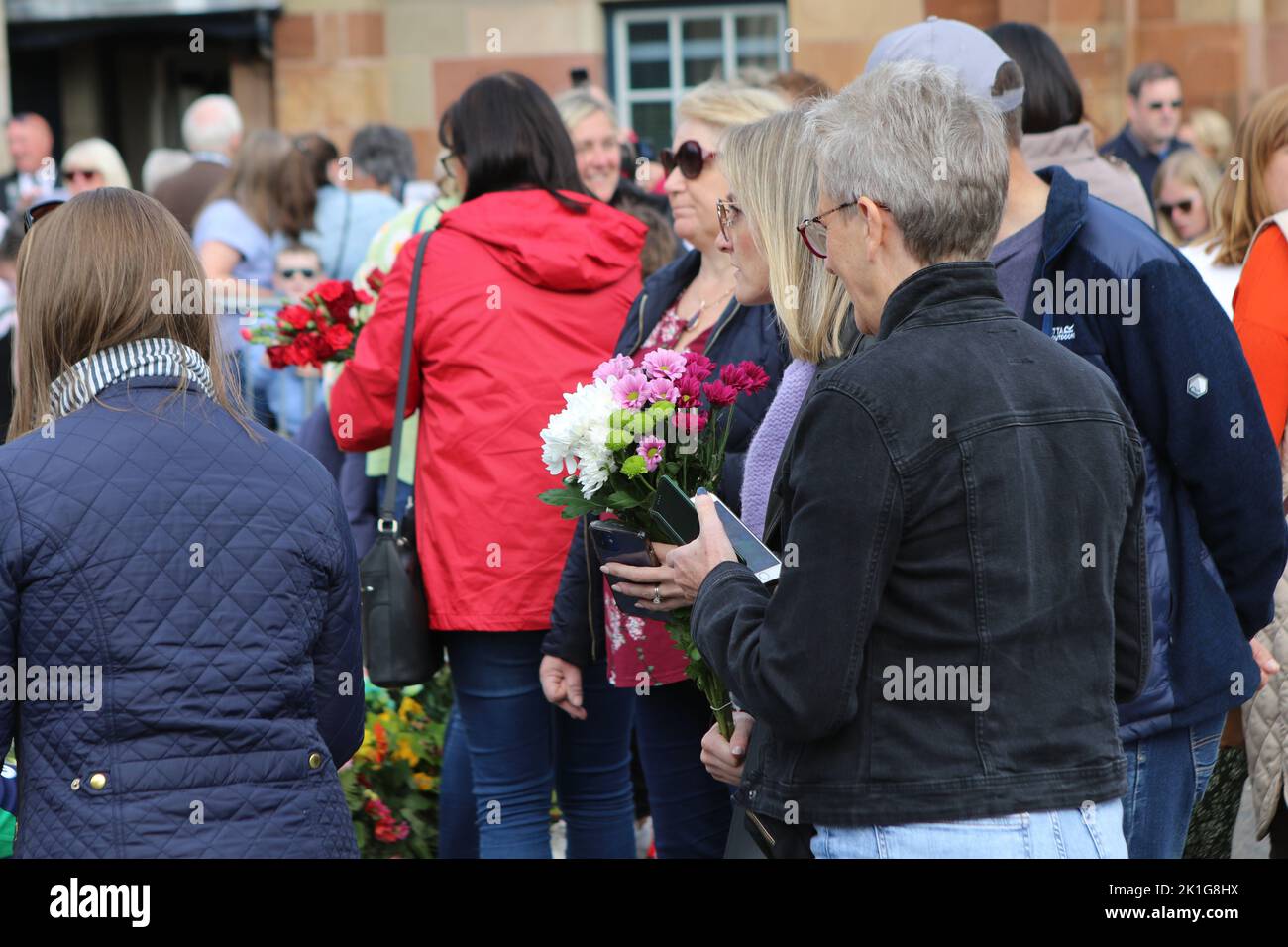 A lady caries some flowers to lay at the gates of Hillsborough Castle
