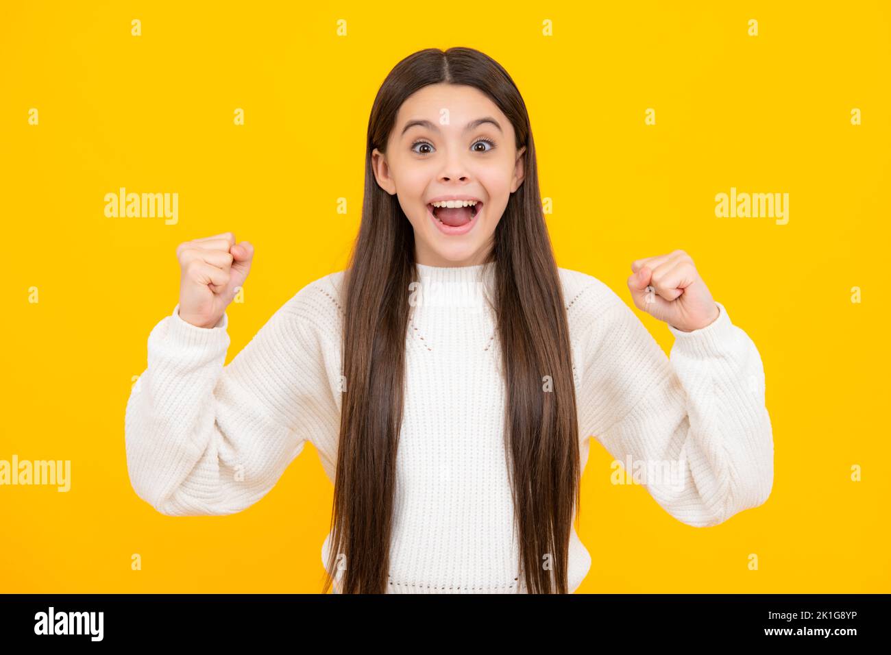 Teenager child girl rejoicing, say yes, looking happy and celebrating victory, champion gesture, fist pump, on yellow background. Stock Photo