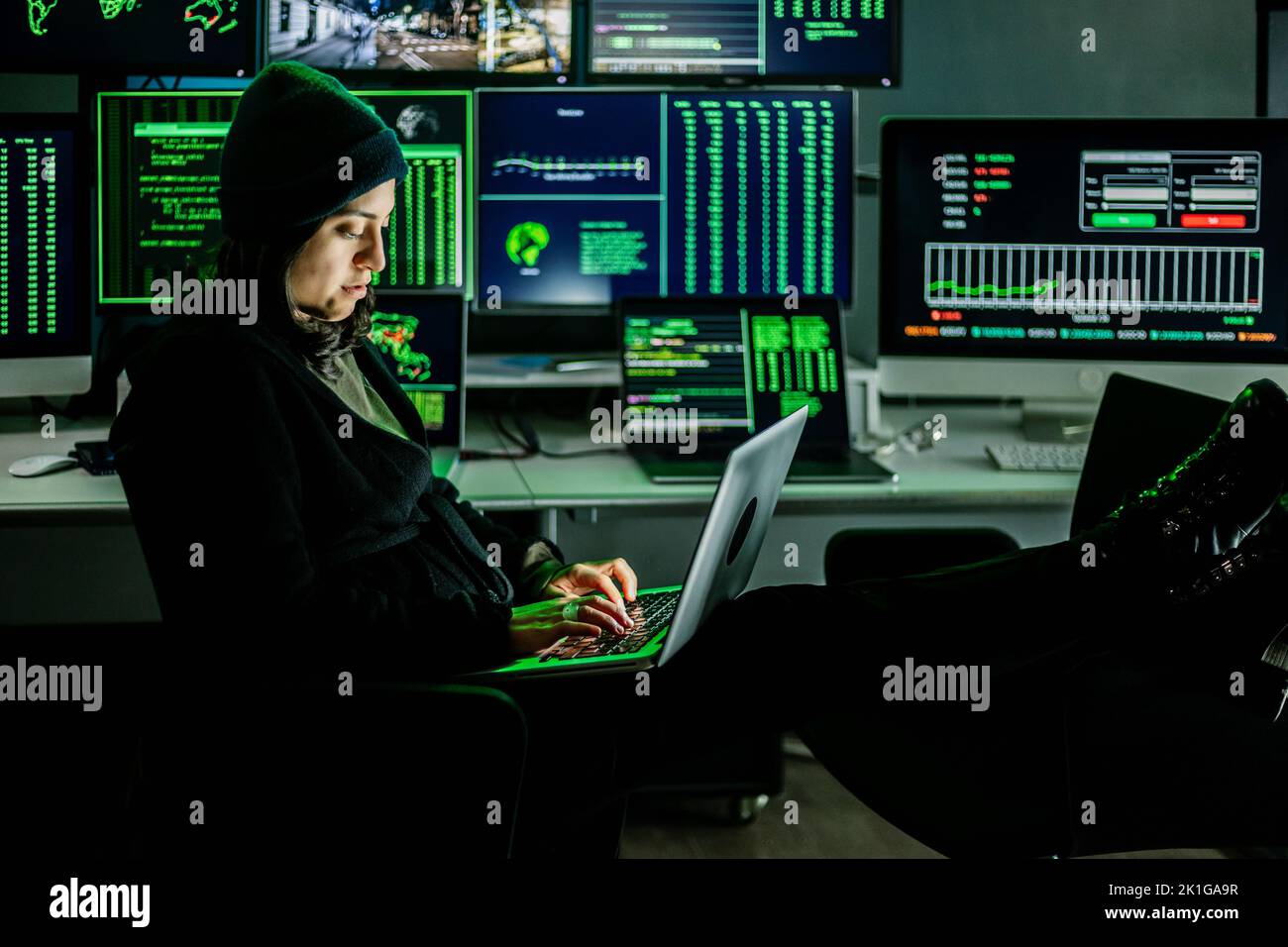 Professional female hacker typing virus code on laptop for cyber attack Stock Photo