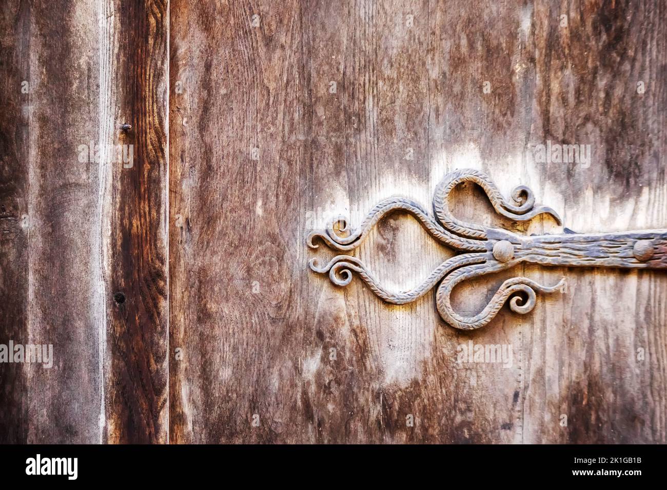 Forged metal hinge on a wooden door Stock Photo