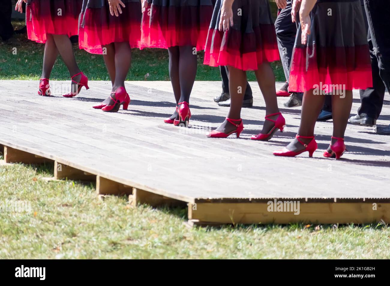 The dance team dances on the light brown stage with pink shoes and black and pink skirts Stock Photo