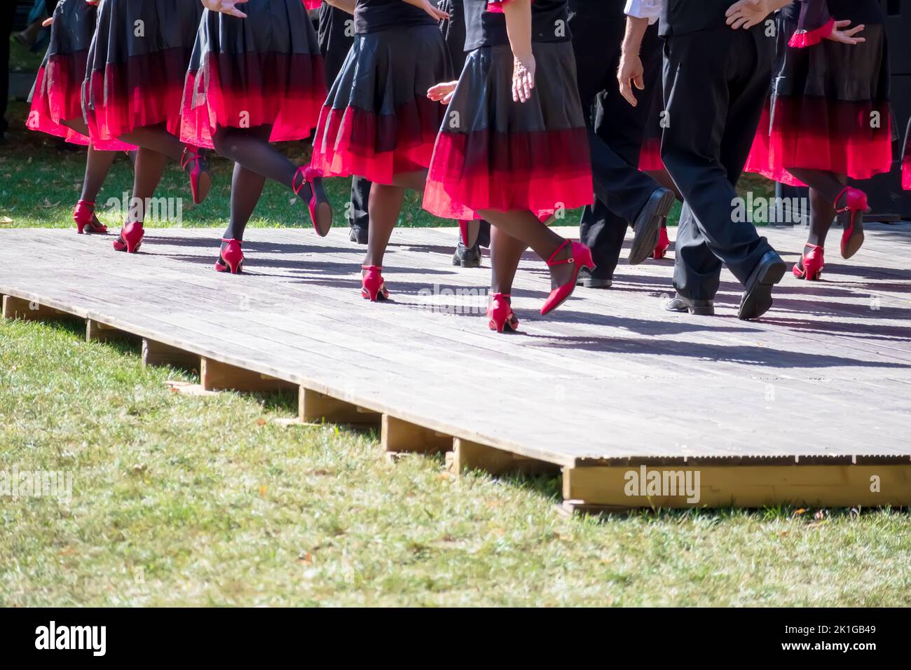 The dance team dances on the light brown stage with pink shoes and