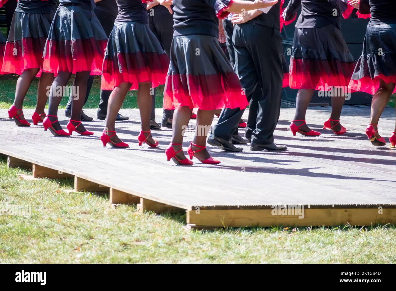 The dance team dances on the light brown stage with pink shoes and black and pink skirts Stock Photo