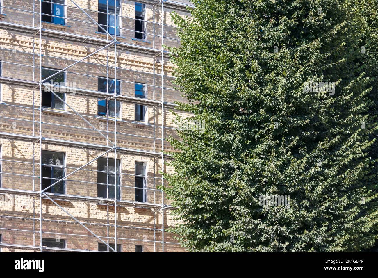 A brown brick house with metal racks and a dark green tree next to it ...