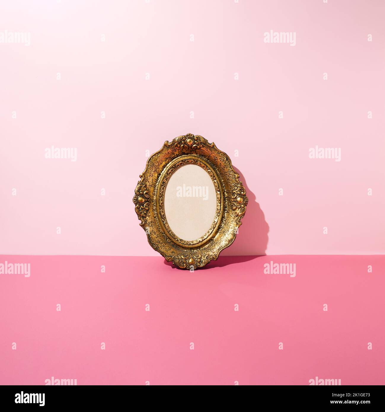 Vintage golden photo and picture frame leaning against pink wall. Minimal concept. Stock Photo