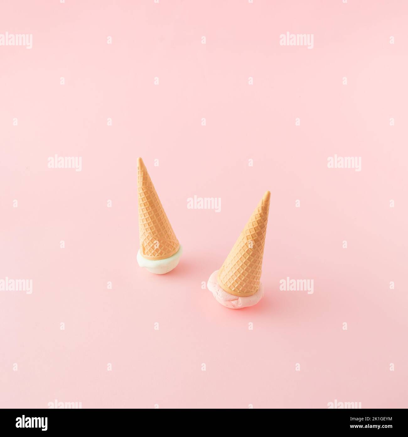 Two ice cream cones with green and pink scoops turned upside down on pink background. Top view. Minimal concept. Stock Photo