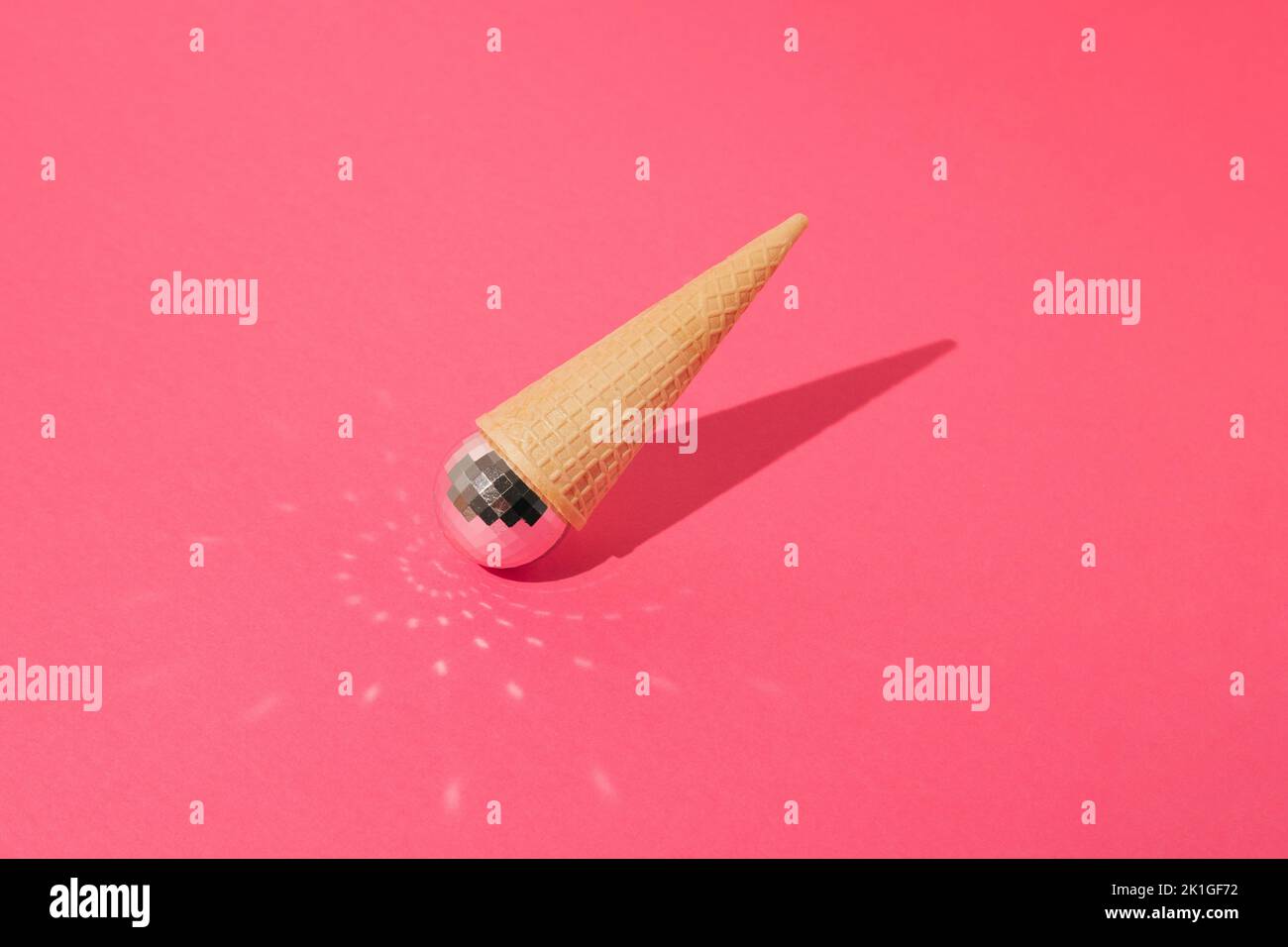 Ice cream cone with shiny disco ball turned upside down on pink ...