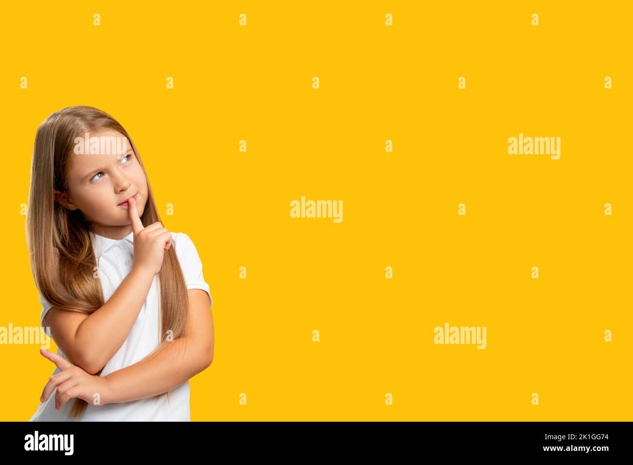 Curious kid. Commercial background. Special offer. Portrait of pensive unsure young girl thinking considering invisible option isolated on yellow empt Stock Photo