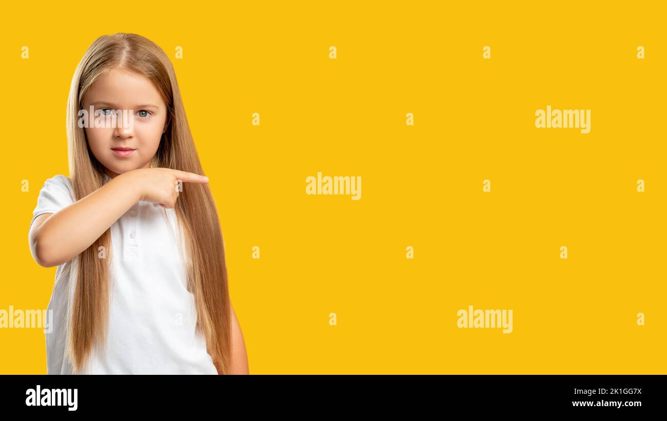 Special offer. Commercial background. Sale discount. Confident little girl showing presenting pointing finger at invisible product information text is Stock Photo