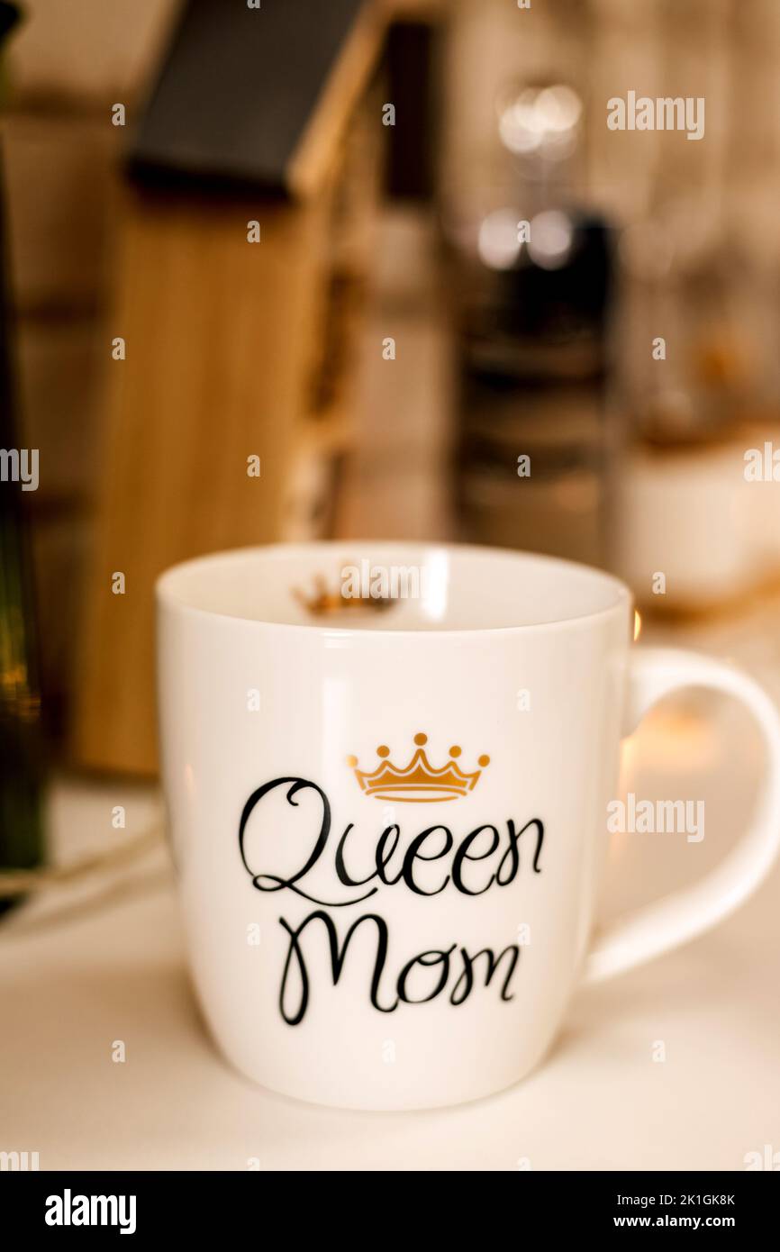 A white cup with the inscription Queen Mama stands on the table in the kitchen Stock Photo