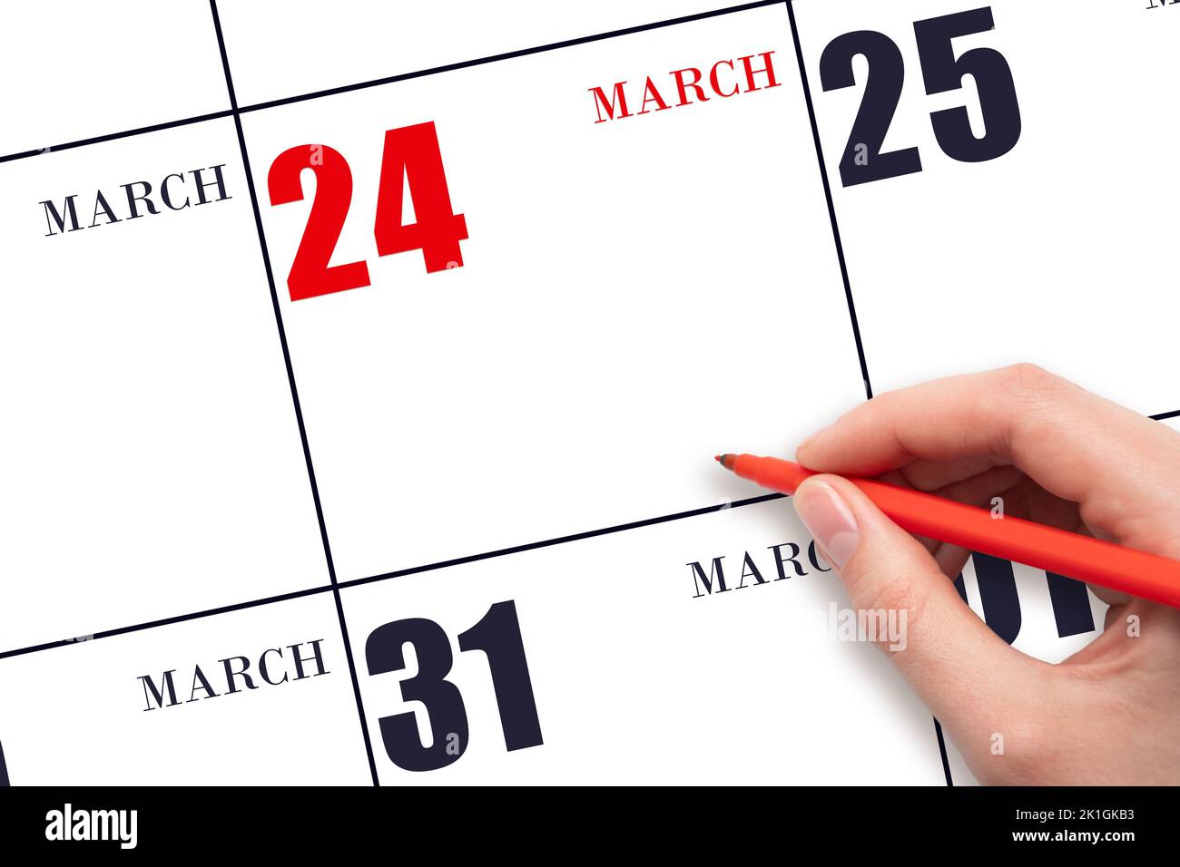 24th day of March. A hand holding a red pen and pointing on the