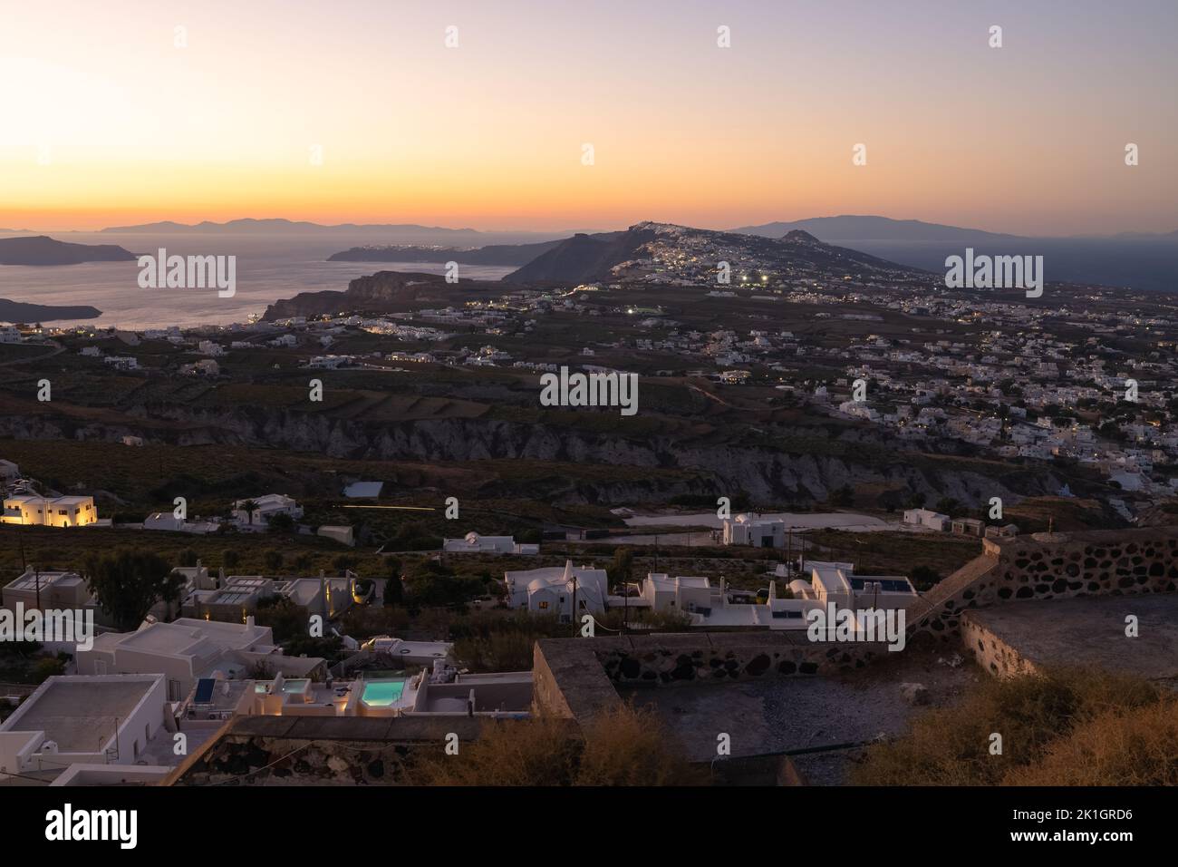 Cityscape and countryside view of Thera, the capital city of Santorini in the Greek Islands of Greece, on a hilltop of volcanic rock during colourful Stock Photo