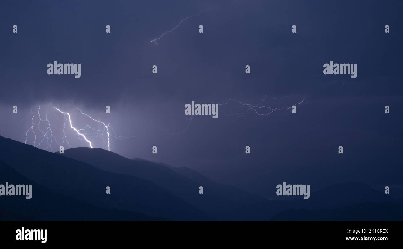 A scenic view of lightning striking at night on hills Stock Photo