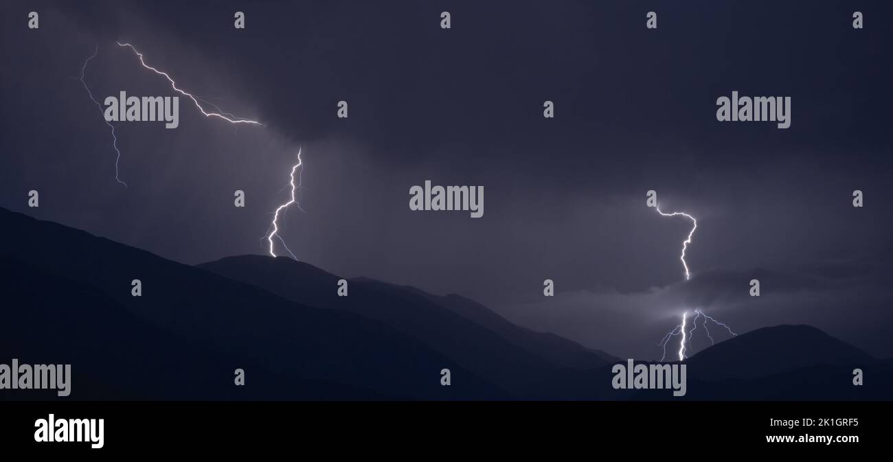 A scenic view of lightning striking at night on hills Stock Photo