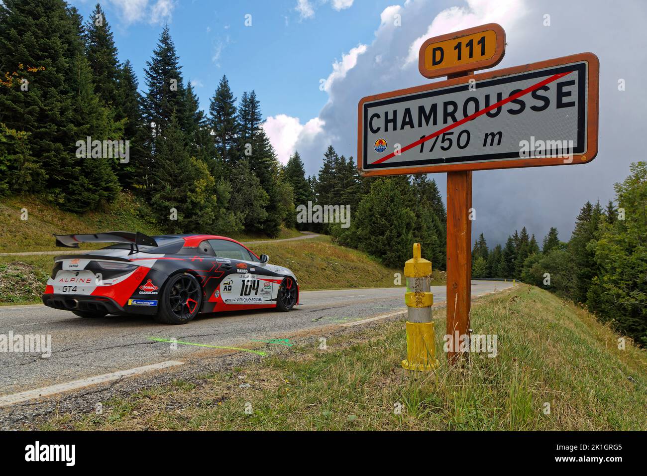 CHAMROUSSE, FRANCE, August 20, 2022 : A racing car runs in front of Chamrousse roadsign during uphill race. Hillclimbing is a branch of motorsport in Stock Photo