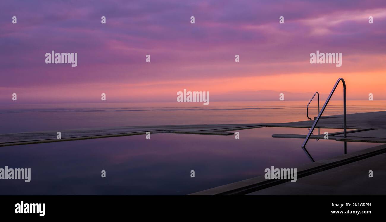 The aesthetic view of a pool and the sea at sunset. Stock Photo
