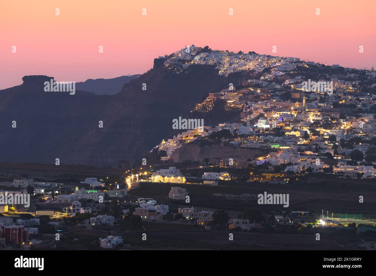 Cityscape and countryside view of Thera, the capital city of Santorini in the Greek Islands of Greece, on a hilltop of volcanic rock during a vibrant, Stock Photo