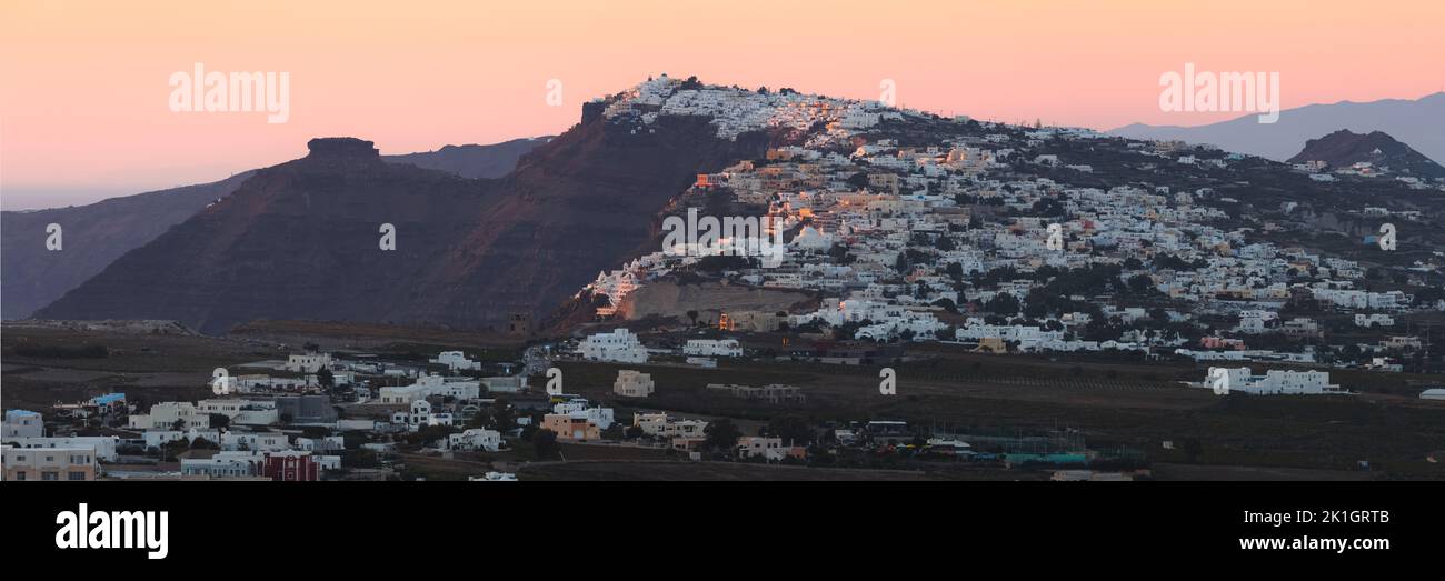 Cityscape and countryside wide panorama view of Thera, the capital city of Santorini in the Greek Islands of Greece, on a hilltop of volcanic rock dur Stock Photo