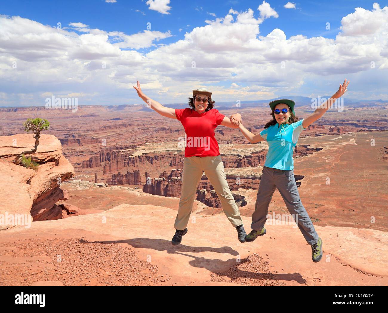 Young daughter and mother tourists jumping happy in Canyonlands National Park, Utah, USA Stock Photo