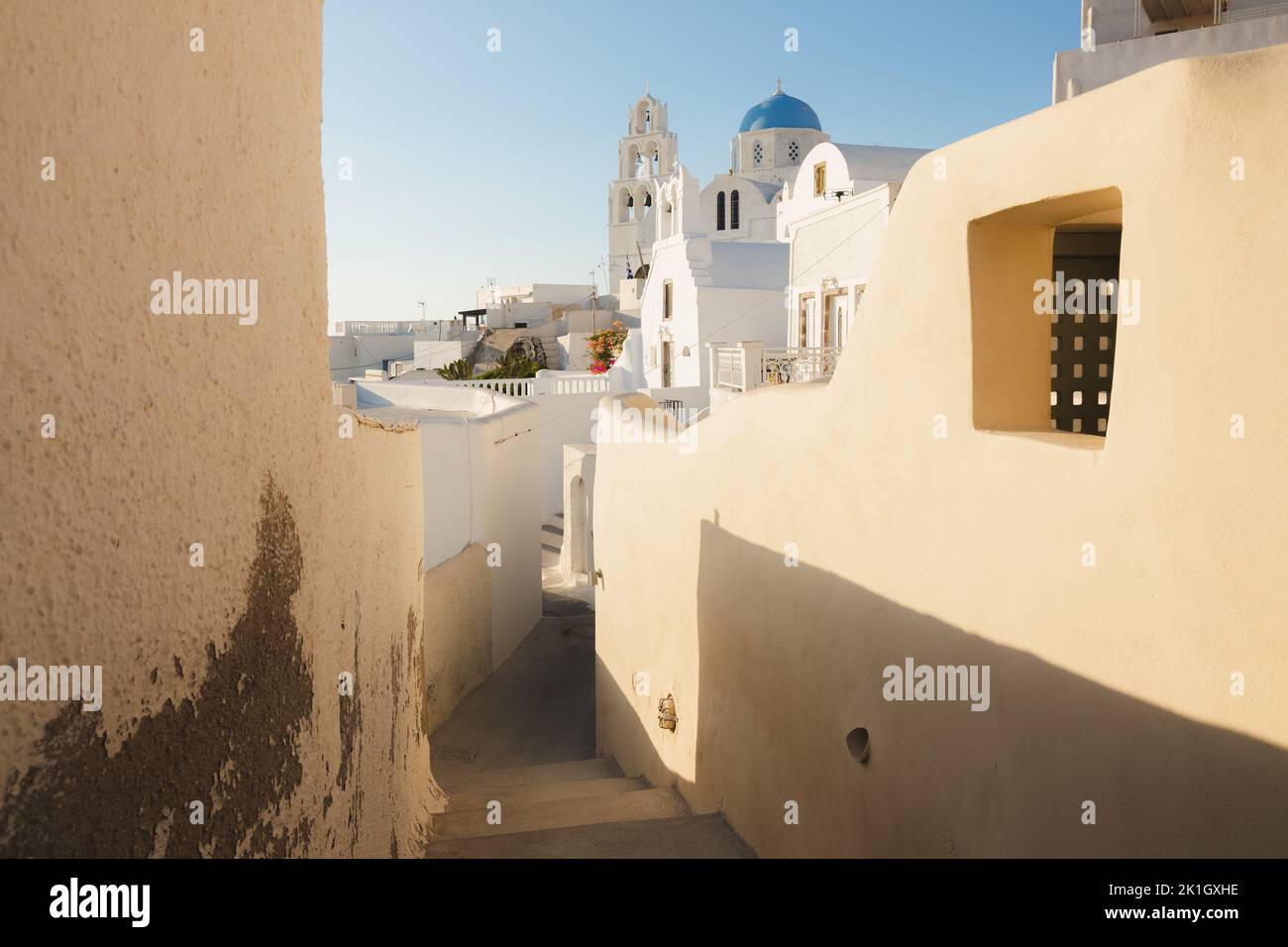 A narrow old town lane in the quaint village of Pyrgos Kallistis leads to the traditional blue dome Greek Orthodox Saint George Church on the island o Stock Photo