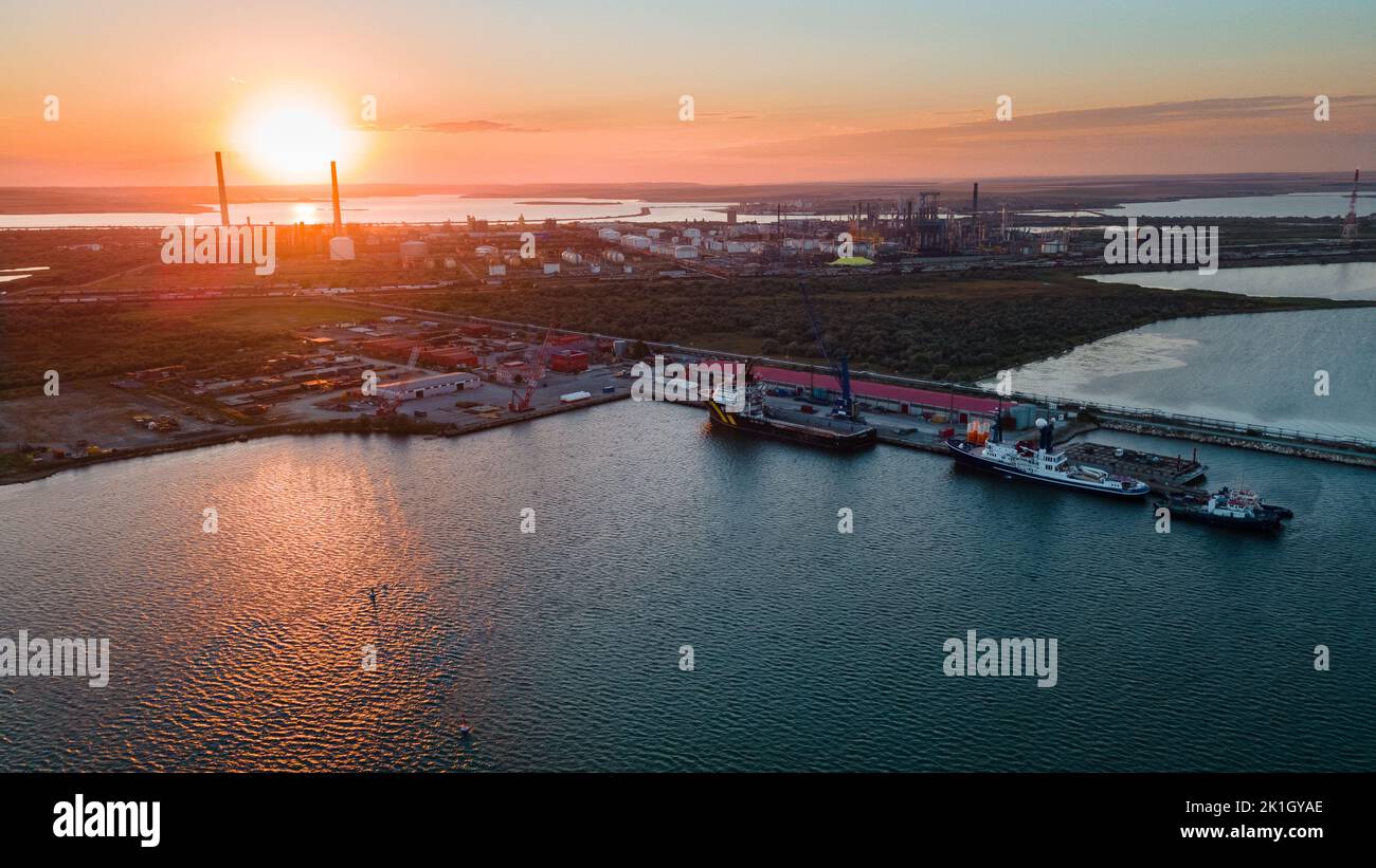 Aerial view of a harbor with ships sailing and docked. Photography was taken from a drone at a higher altitude in summer season at sunset. Stock Photo