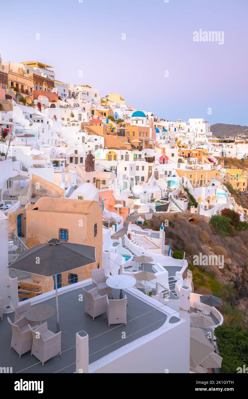 Seaside view at blue hour of traditional white wash buildings and blue dome church at the popular seaside tourist resort village of Oia on the Greek i Stock Photo