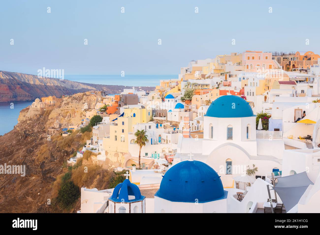 Seaside view of traditional white wash buildings and colourful blue dome churches at the popular seaside tourist resort village of Oia on the Greek is Stock Photo