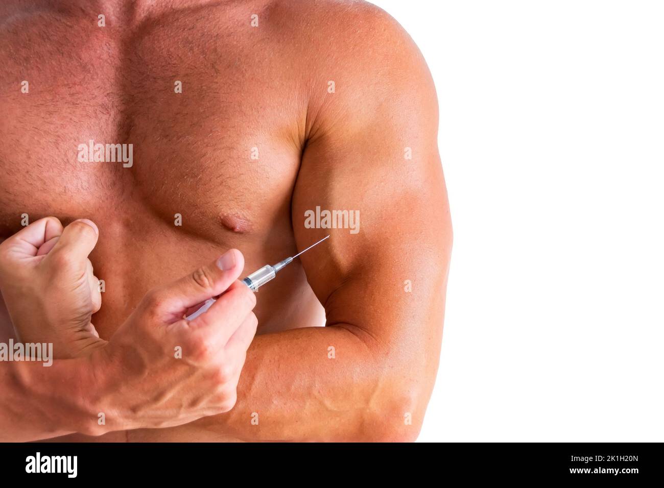 Bodybuilder holding an injection of a steroid syringe to his chest. Strong athletic rough muscular man pumps up abdominal muscles, exercising, doing f Stock Photo