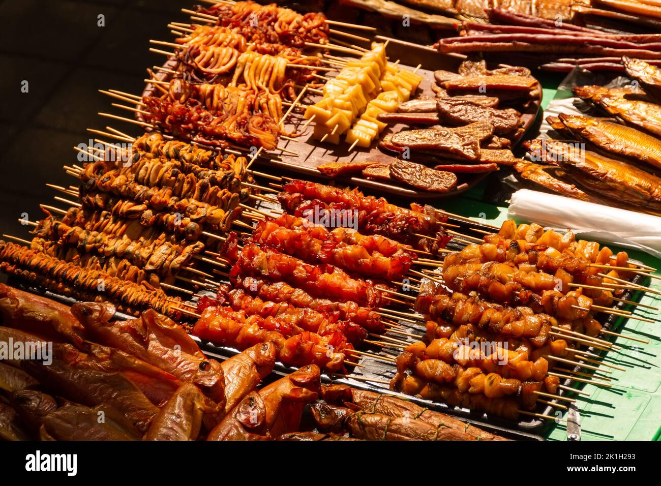 Mussels, squids, fish, shrimps and many other smoked and dried seafood on the market counter. Meat on skewers, sticks Stock Photo
