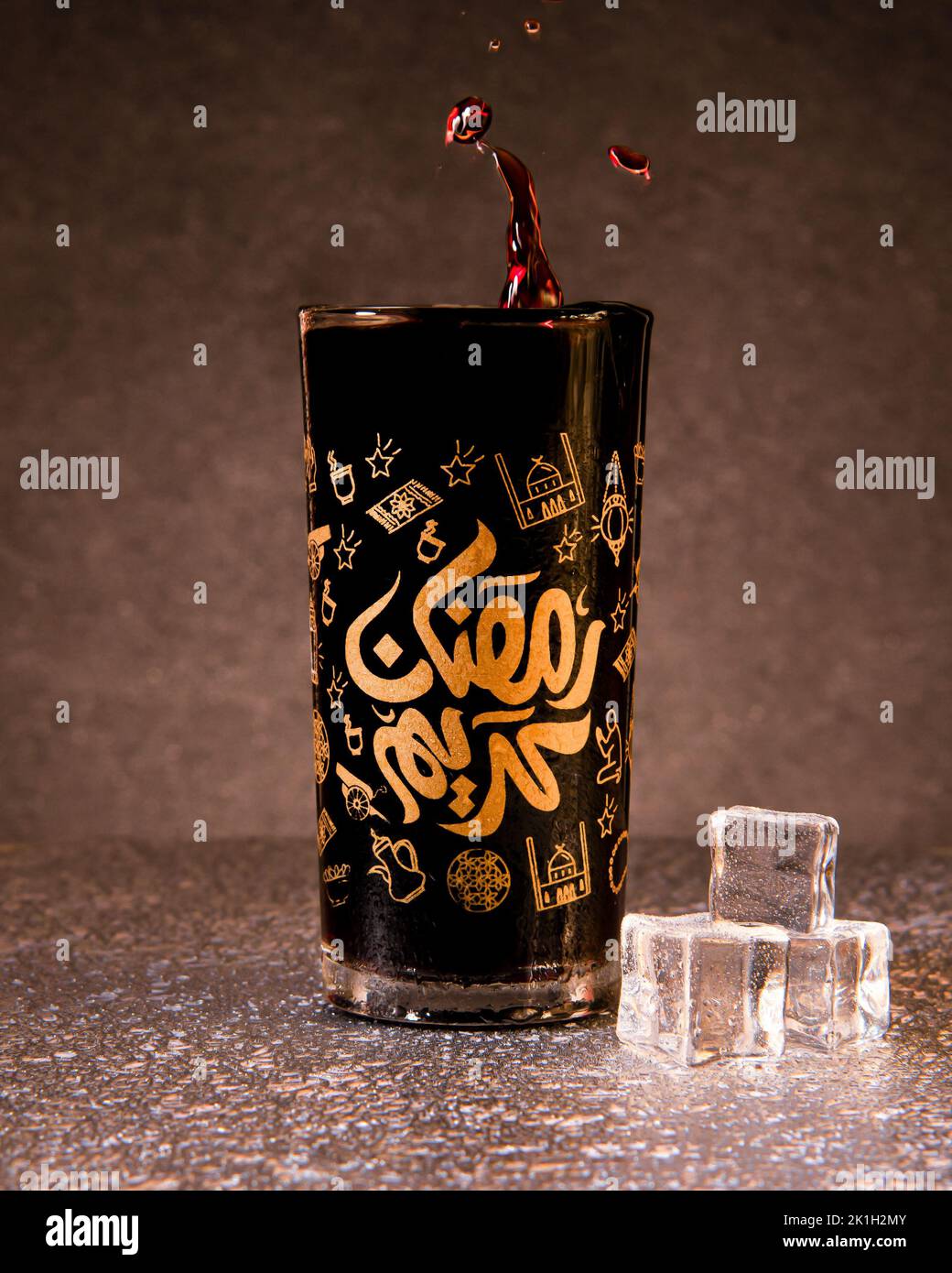 A closeup shot of a glass cup with 'blessed Ramadan' writing in Arabic with a juice splash Stock Photo