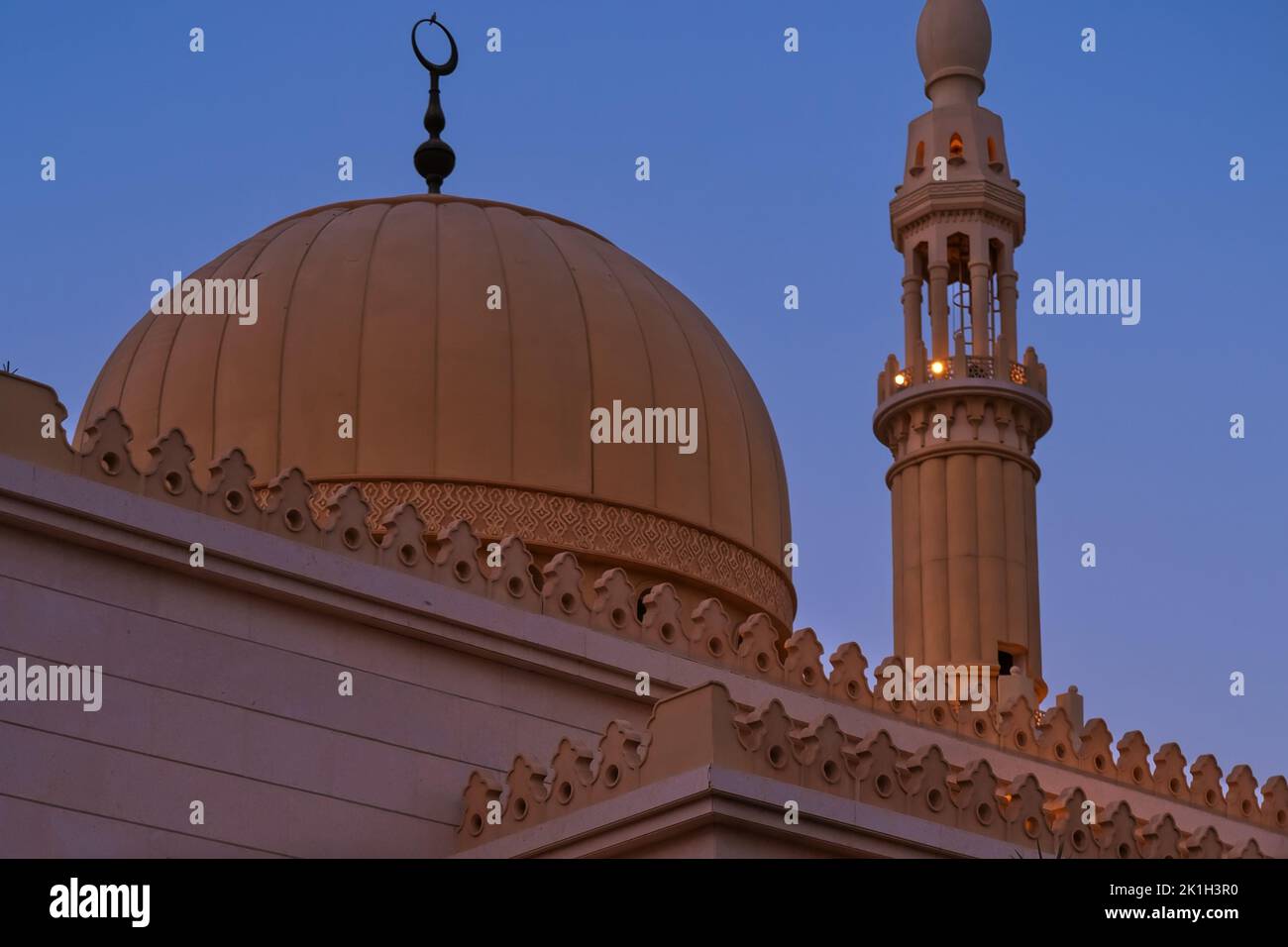 Minaret and dome of Muslim Islamic mosque on sunset background. Minaret tower and roof cupola with traditional crescent Stock Photo