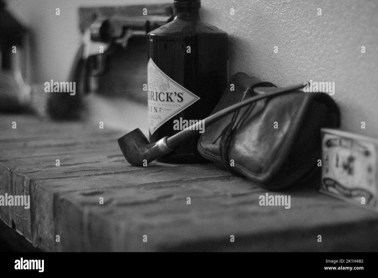 A closeup of a vintage Pipe and old objects on a brick fireplace mantel in greyscale Stock Photo