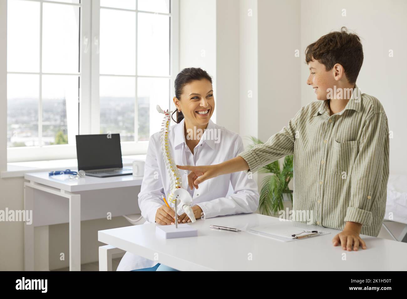 Happy, smiling child and doctor at orthopedic clinic talking about skeleton and spine Stock Photo