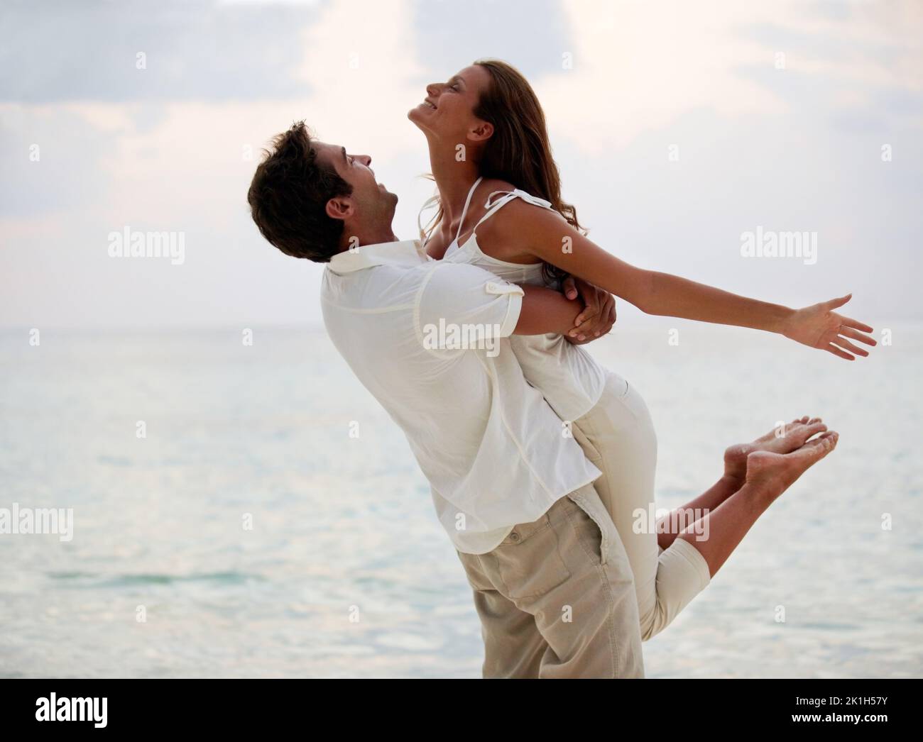 Unrestrained happiness. A young beauty feeling light and free as her boyfriend lifts her into the air on the beach. Stock Photo