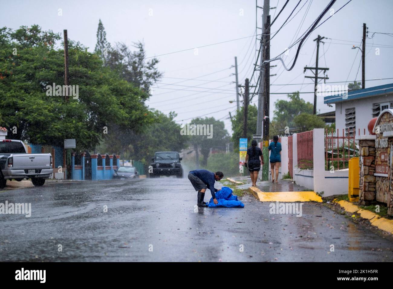 A person recovers a blue tarp form the road as Hurricane Fiona made