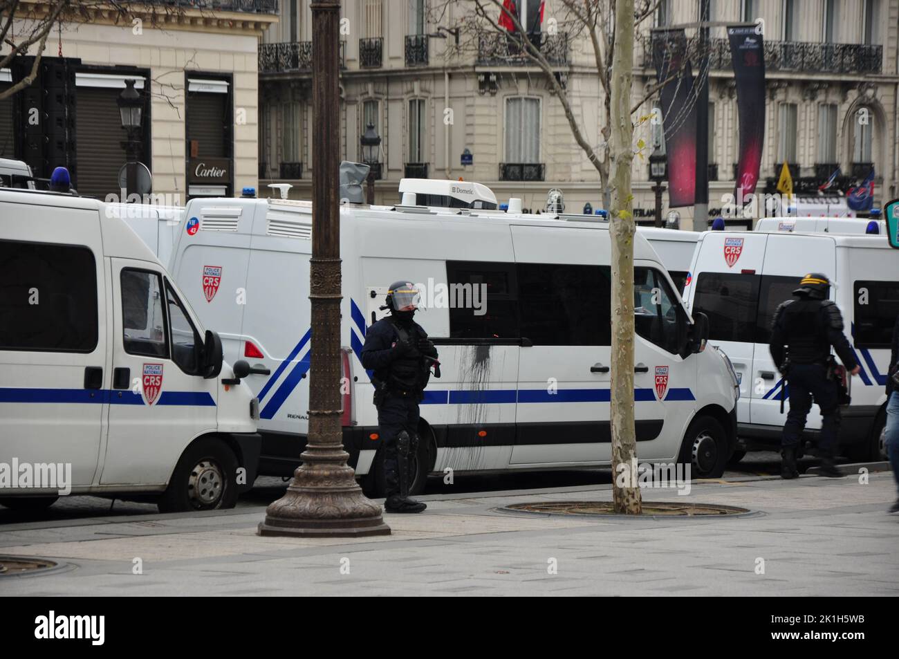 Police officers wearing helmets and carrying batons in front of police buses on Avenue des Champs-Elysees during yellow vests protests in Paris Stock Photo