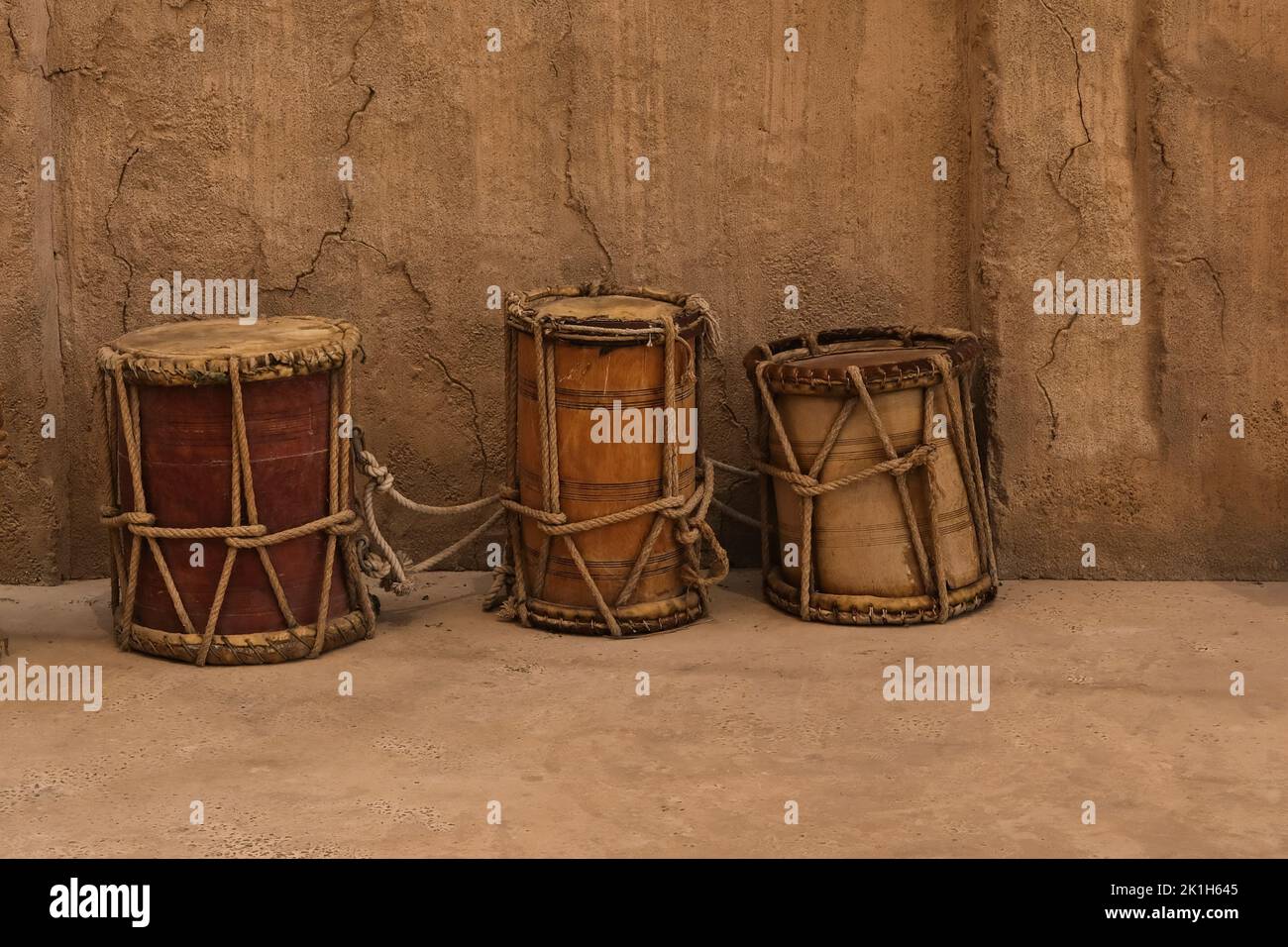 Ancient authentic folk music wooden drums in Africa and Gulf Persian Countries. Middle Eastern hand-made drums on sand wall background.  Stock Photo