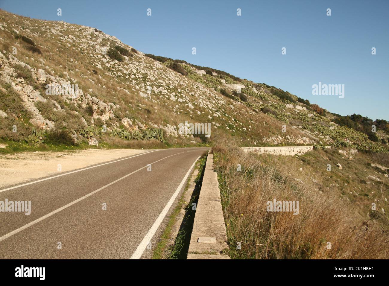 Puglia, Italy. Road by the shore of the Adriatic Sea, with rugged terrain on the sides, in wintertime. Stock Photo