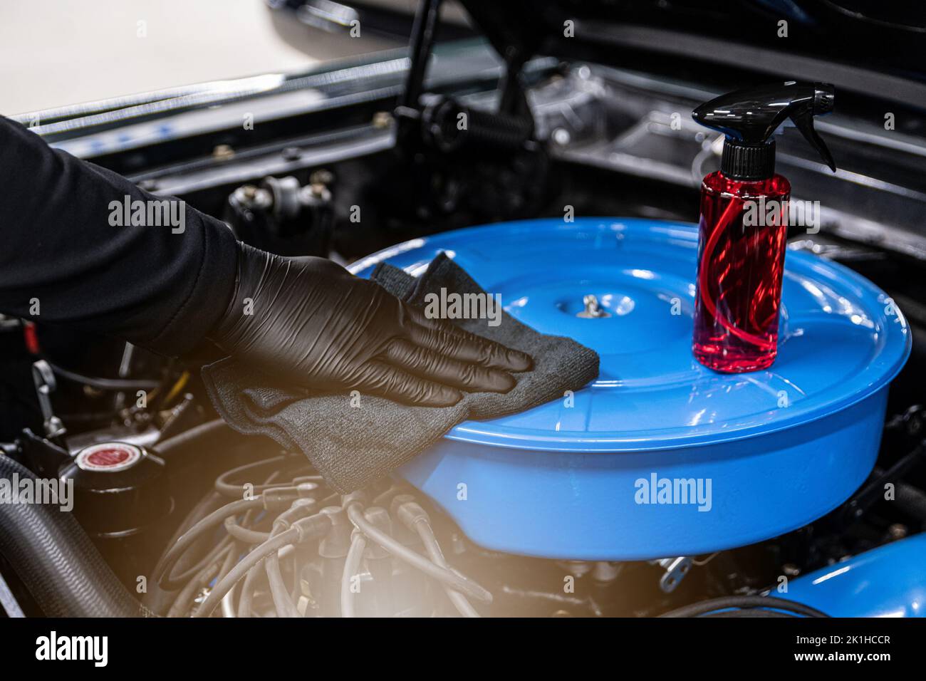 Car mechanic or car wash worker will clean the car engine with a cloth