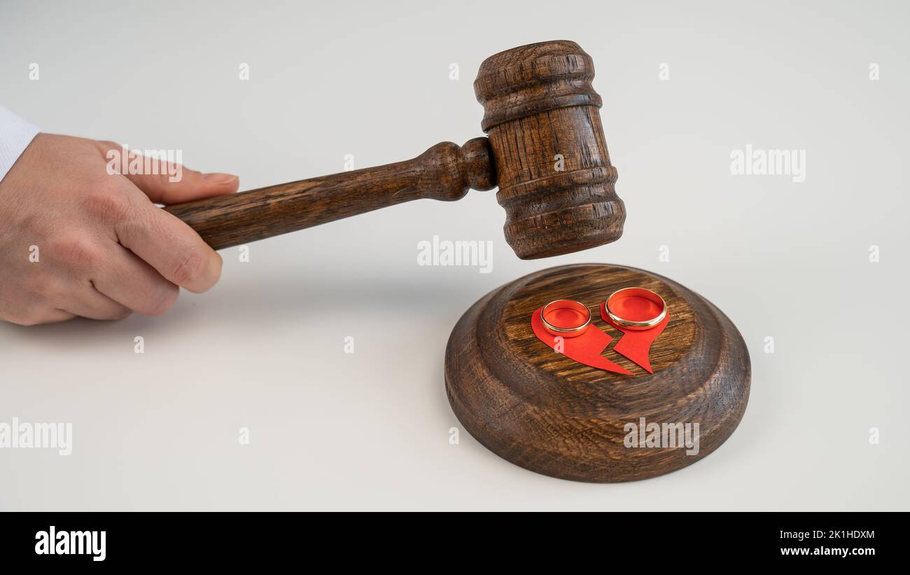 The judge hits the gavel on a broken heart and wedding rings Stock