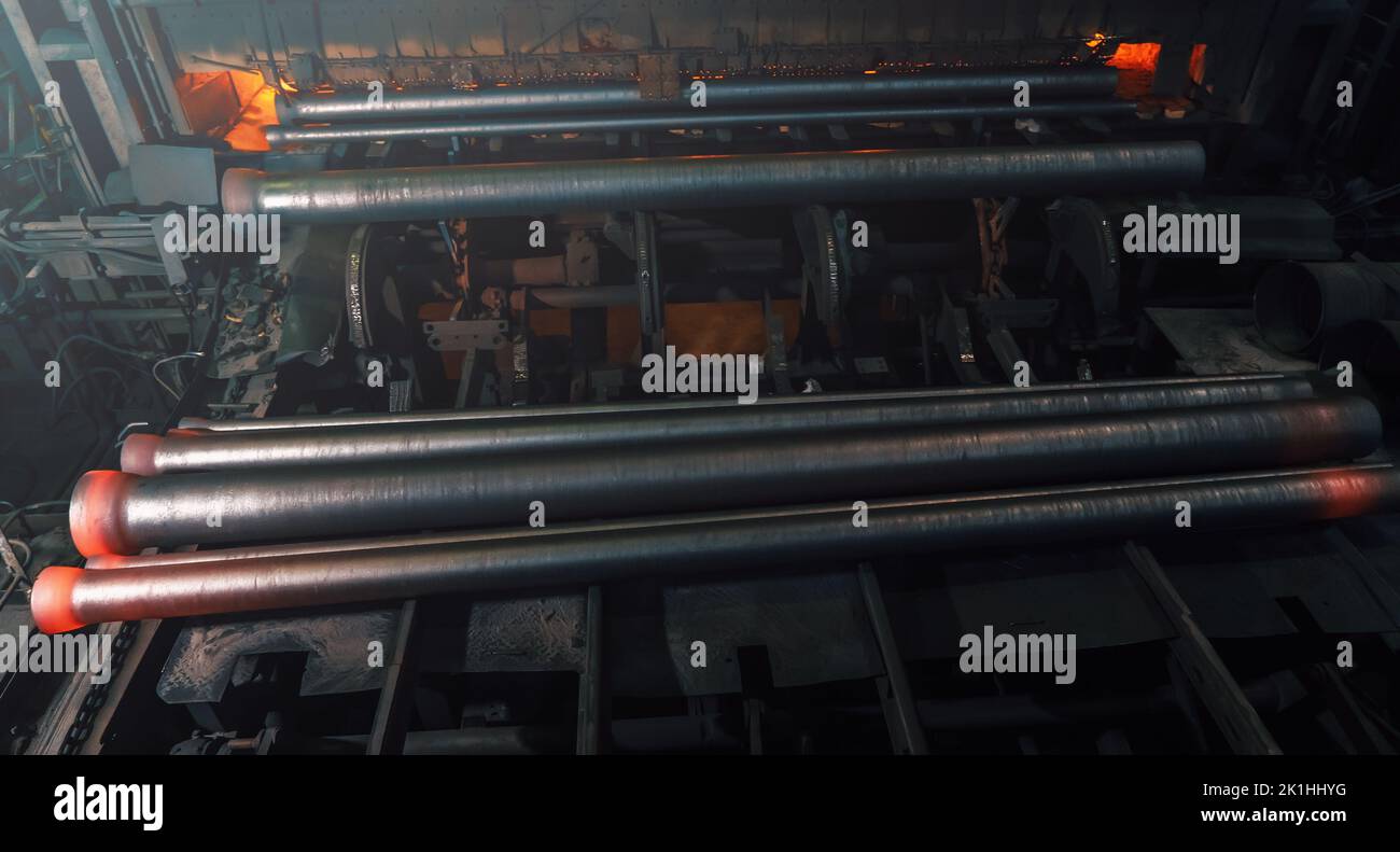 Freshly cast hot cast iron pipes at smelter. Manufacture of pipes for water, gas or oil. Stock Photo